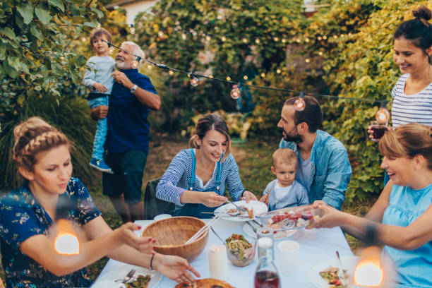 Photo of a multi-generation family having dinner outdoors in their back yard